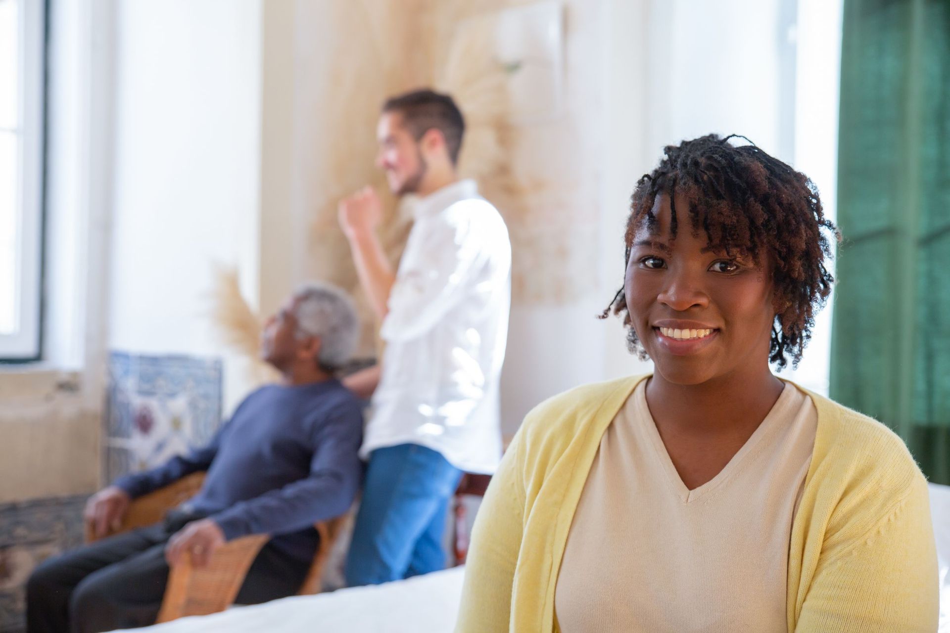 A smiling carer, with a colleague and client in the background