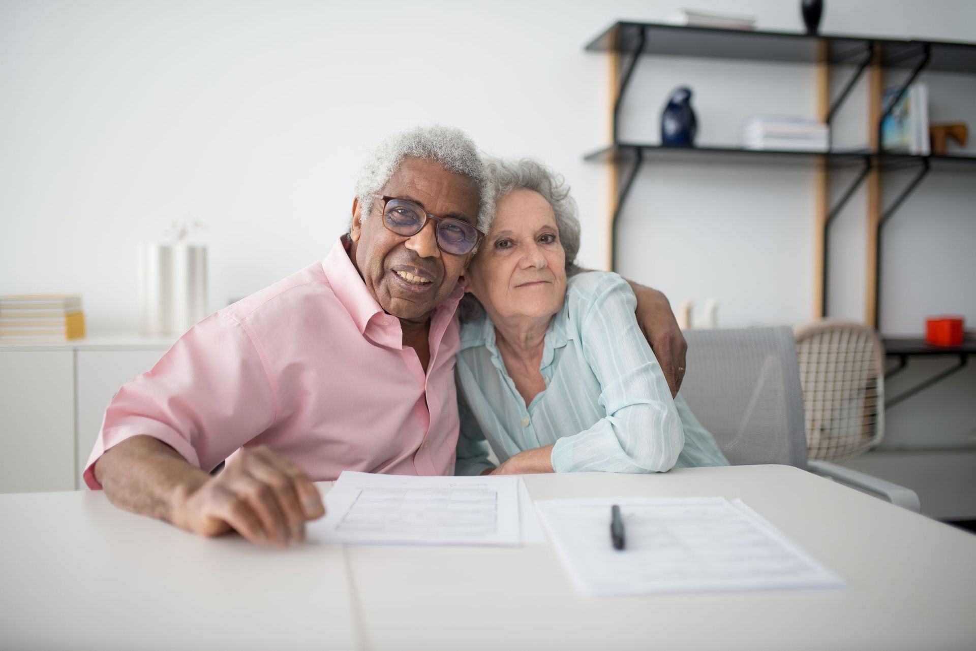 An older couple smiling as they go through paperwork at the table