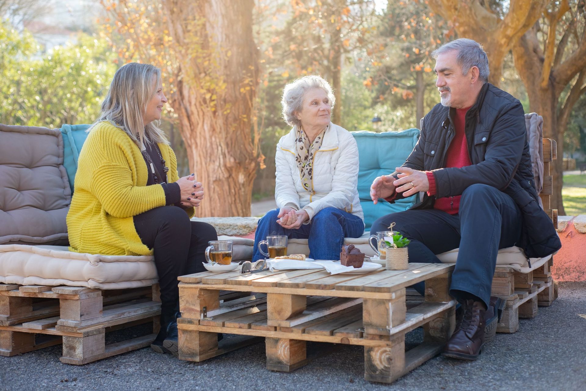 Older friends chatting over tea outdoors in the sun