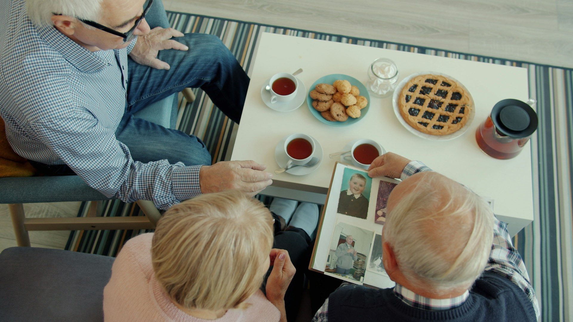 Older people sitting together over tea and a photo album