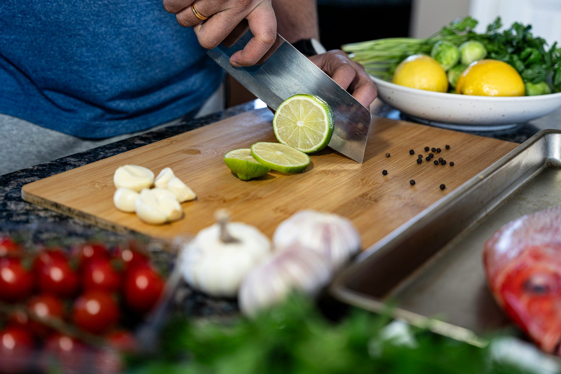 Hands slicing limes and garlic on a wooden board