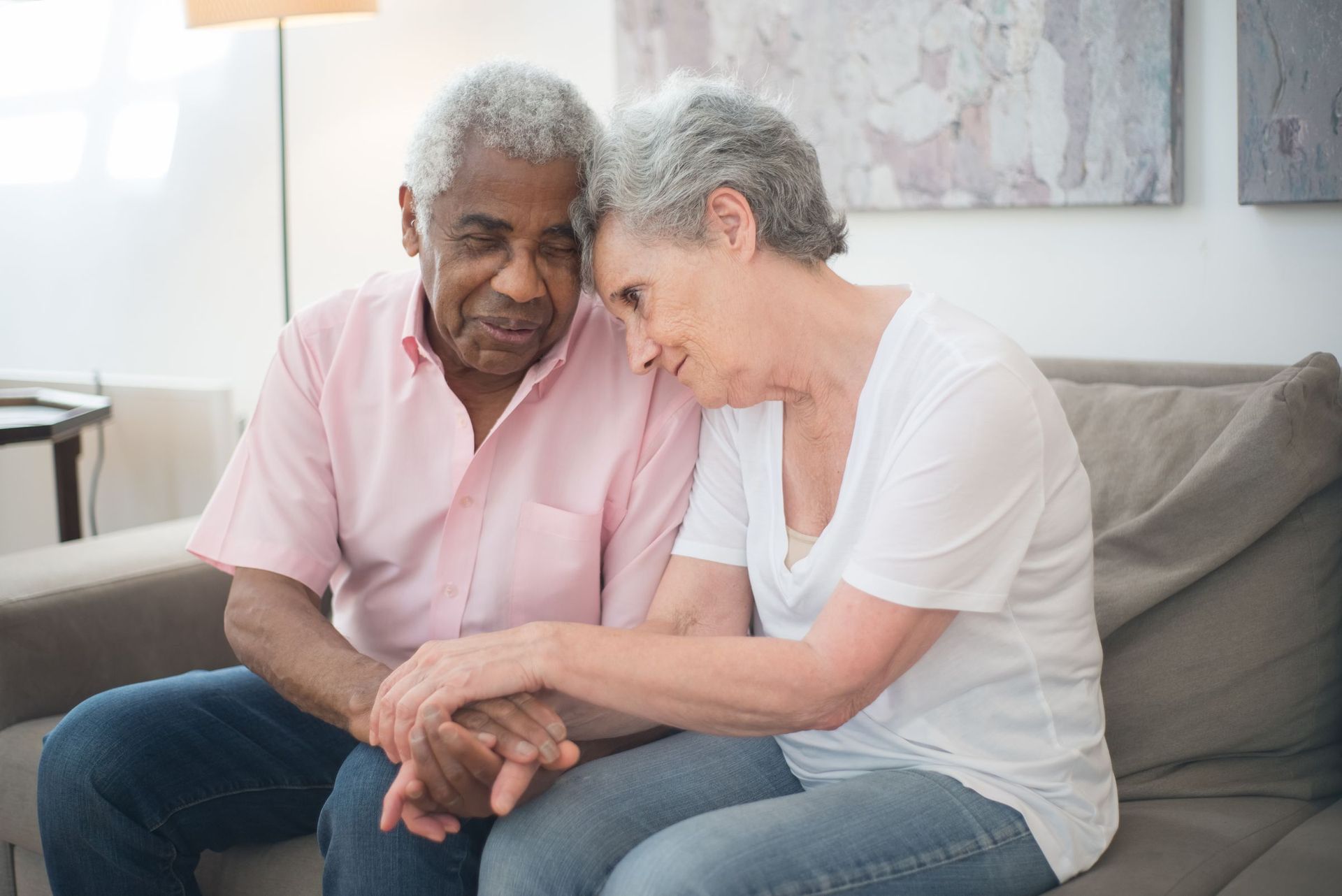 An older couple sitting close together on their sofa at home