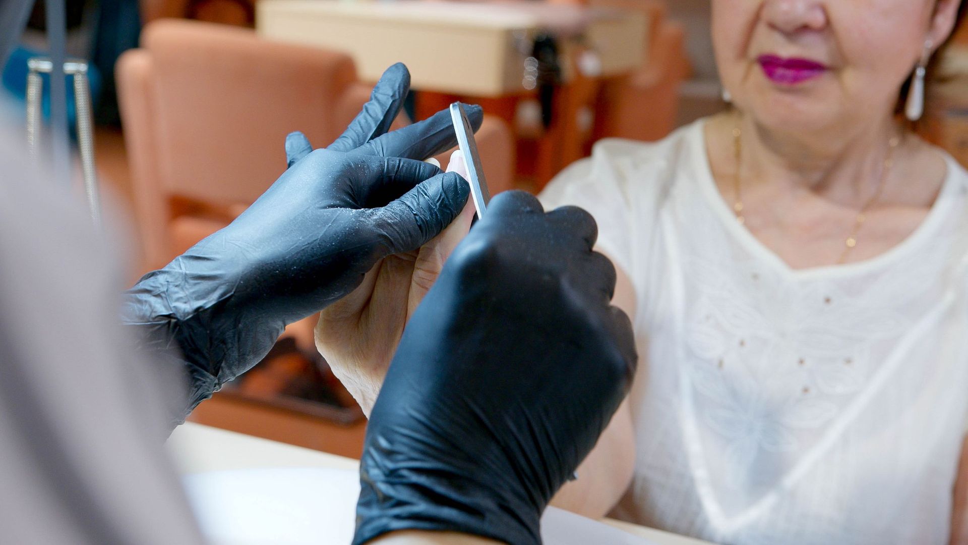 An older woman having her nails gently filed