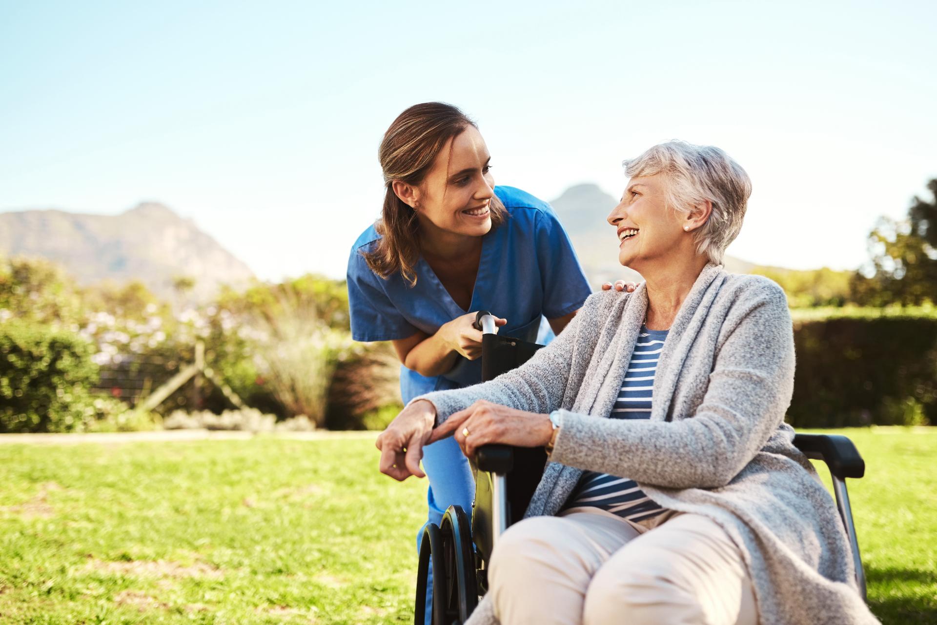 A support worker and a resident laughing together in a sunny garden