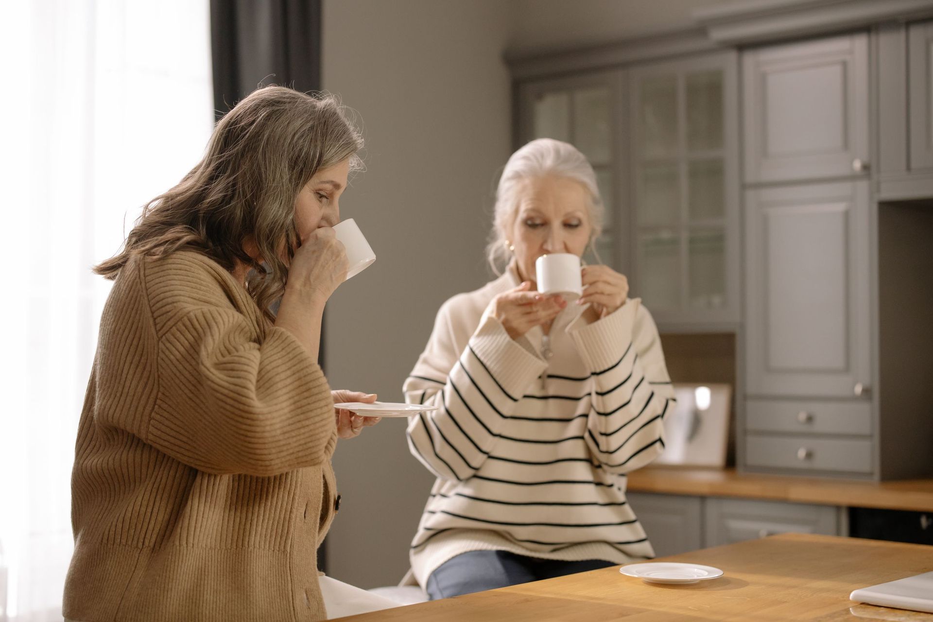 Two women having a cup of tea together in a kitchen